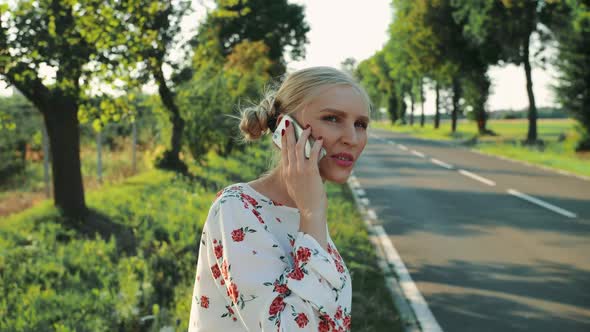 Woman Speaking on Phone While Hitchhiking.