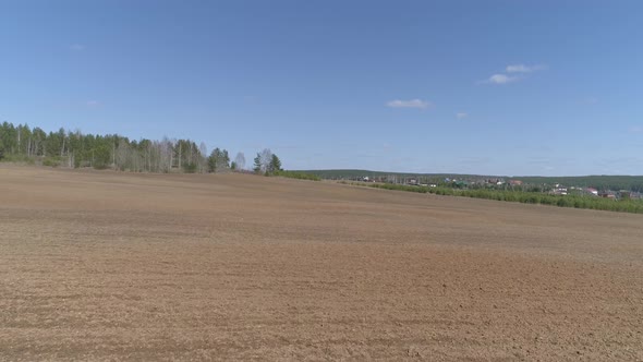 The camera flies low over a plowed field. Sunny spring day. Blue sky. The camera flies forward 04