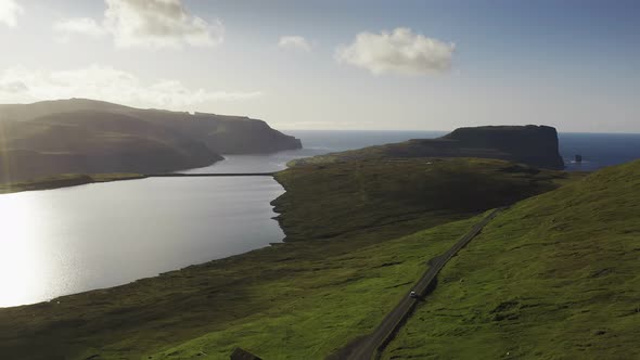 Car Driving Along Coastal Road View on Wild Green Island at Sunset