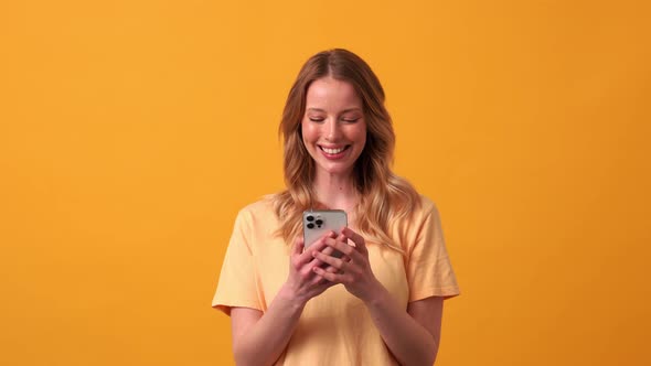 Positive blonde woman wearing yellow t-shirt typing by phone