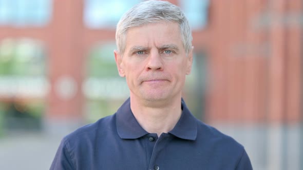 Outdoor Portrait of Middle Aged Man Shaking Head As No Sign