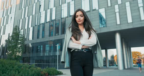 Smiling Girl with Brown Hair Stands of Corporate Building for Break Dressed in Smart Shirt and