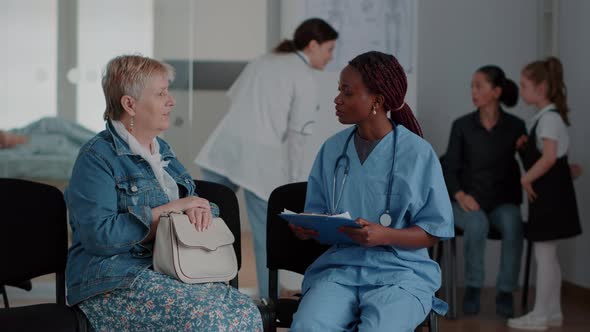 African American Nurse Explaining Diagnosis to Elder Woman in Waiting Room