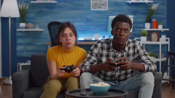 Modern Interracial Couple Playing with Joysticks for Video Game