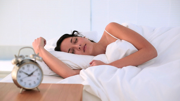 Brunette Being Woken By Her Alarm Clock In Bed