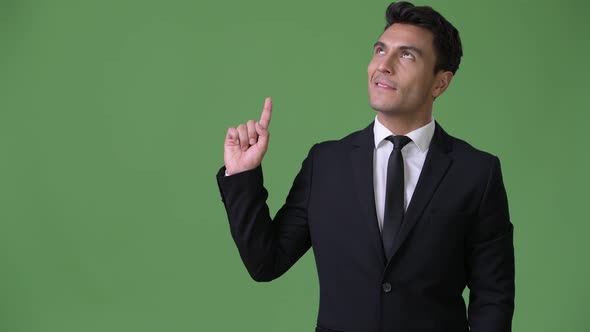 Young Handsome Hispanic Businessman Against Green Background