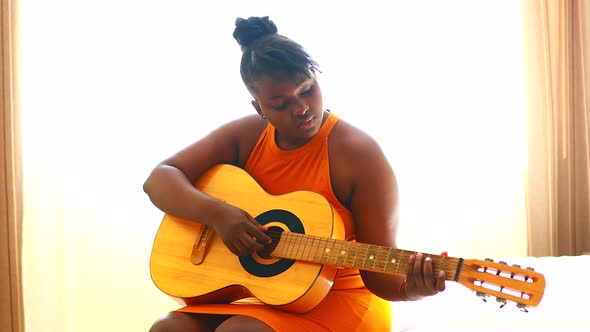 African American Teenage Girl Practicing Her Skill on Acoustic Guitar