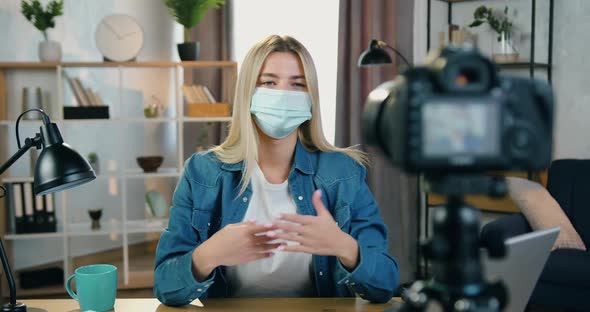 Woman in Facial Mask Recording Video on Camera in Home Studio for Her Internet Audience