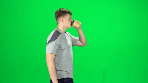 Guy Is Walking and Drinking Coffee From a Paper Cup. Chroma Key. Side View