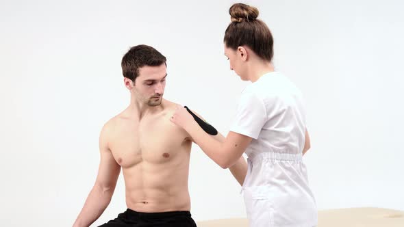 Shoulder treatment with kinesio tape. Physiotherapist applying elastic therapeutic tape 
