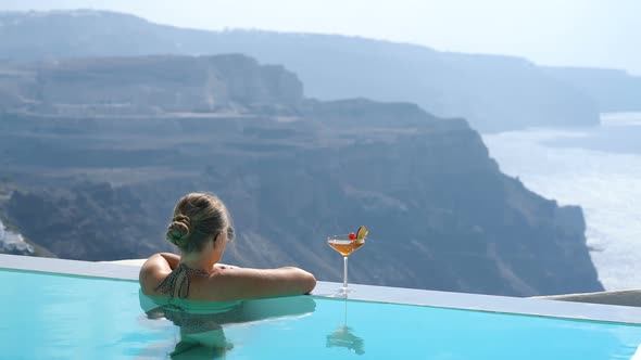 Young Woman Relaxing in the Pool with a Gorgeous View on Santorini