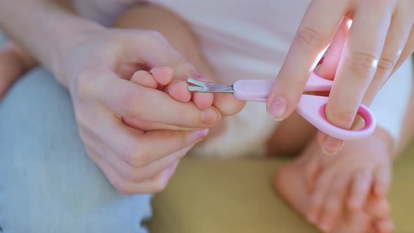 Close Up of a Woman Hands with Scissors Cuts the Toenails of a Baby
