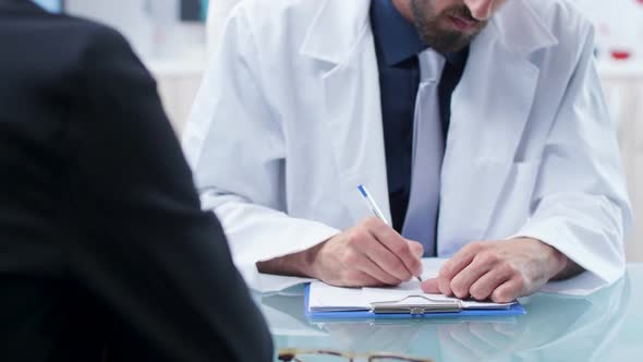 Close Up Shot of Doctor Hands Taking Notes in a Clipboard