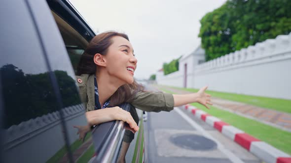 Asian beautiful woman traveler open car window to face air outside.