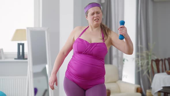 Portrait of Joyful Overweight Woman Lifting Dumbbell Showing Pills Jar Smiling Looking at Camera