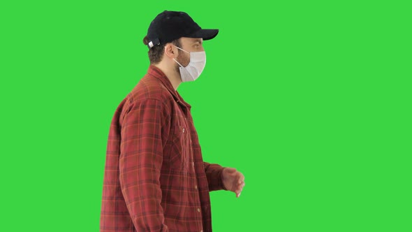 American Farmer in a Cap and Medical Mask Walks Along on a Green Screen, Chroma Key