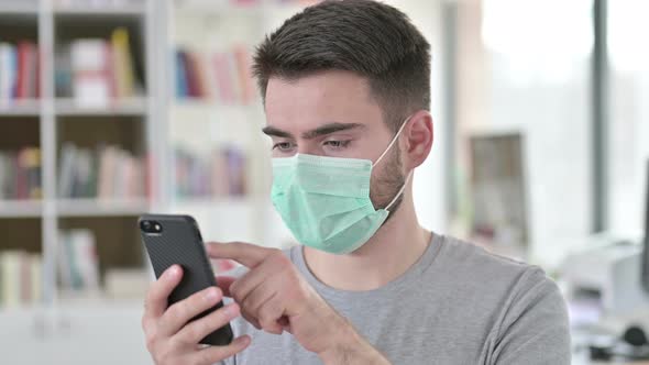 Portrait of Young Man with Face Mask Using Smartphone 