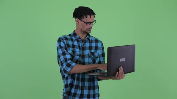 Happy Young African Hipster Man Thinking While Using Laptop