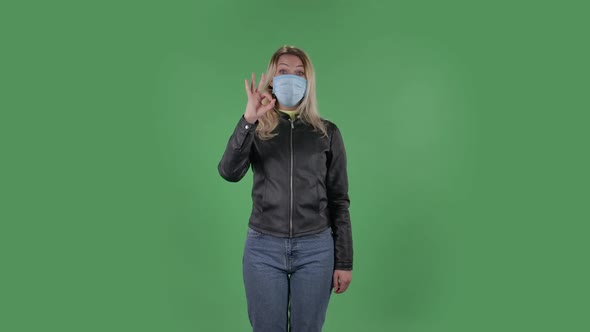 Portrait of Beautiful Young Woman in Medical Mask Is Looking at Camera and Joyfully Making Sign Ok