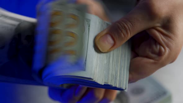 Hands Checks US Dollar Bills or Counting in Cash Against the Backdrop of Police Car Lights