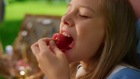 Pretty Girl Eating Strawberry on Summer Picnic Close Up