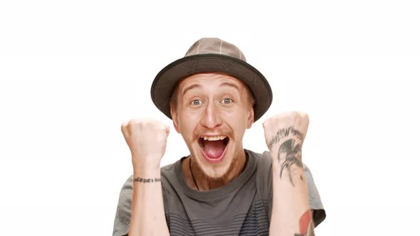 Surprised Young Handsome Man in Hat Smiling Rejoicing Over White Background