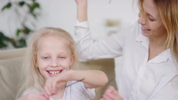 Excited Little Girl and her Happy Mother Trying on Sunglasses at Home