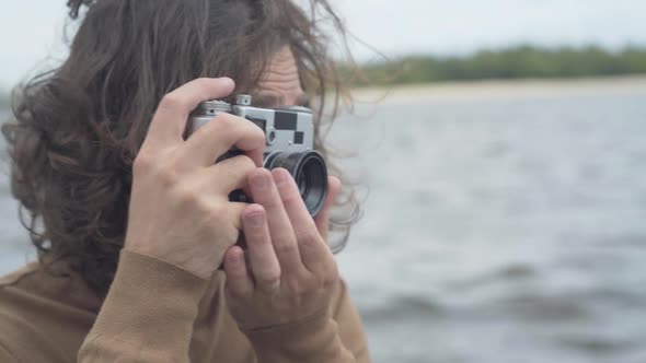 Close-up Face of Happy Caucasian Creative Man Using Retro Camera To Take Photos of Nature. Portrait