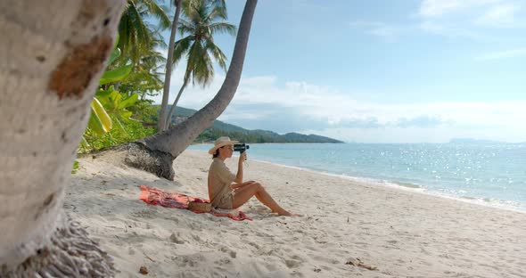 Young Brunette Woman Have a Picnic on the Beach Under the Palms She Sits on the Sand Empty Beach