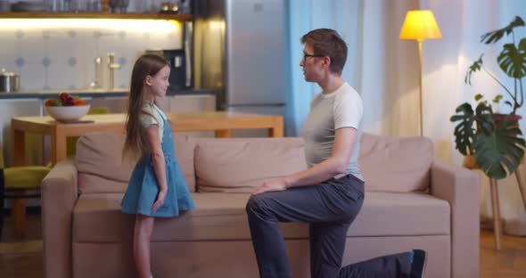 Loving Father Kneeling and Kissing Little Daughter Hand Playing Together at Home