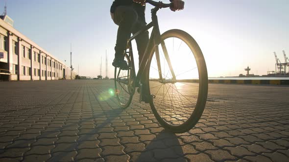 Stylish Handsome Man Riding Bicycle During Sunset or Sunrise with Sea Port on Background Slow Motion