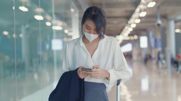 Asian business girl use smart phone for check in boarding pass walk with luggage to terminal.