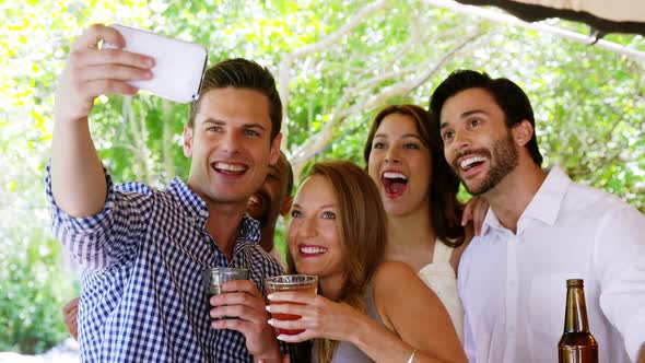 Group of friends taking selfie with mobile phone at bar counter