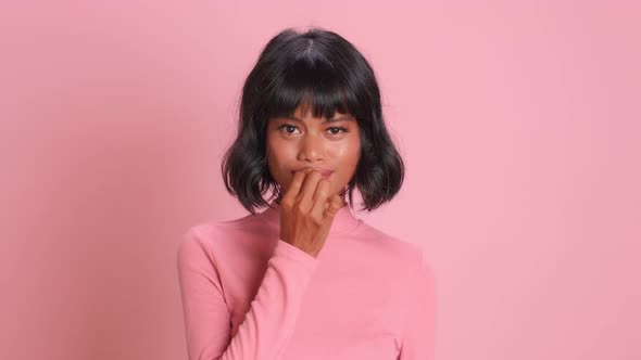 Worried Woman Showing Zip Gesture As Swearing Not to Tell Anyone Over Pink Wall