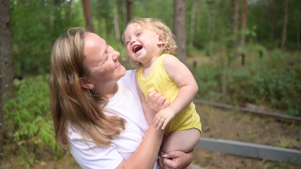 Little Cute Baby Toddler Girl Blonde with Curls on Mother's Arms