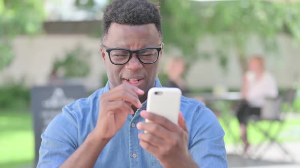 Portrait of African Man Reacting to Loss on Smartphone