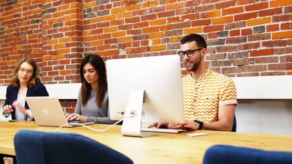 Group of executives discussing over computer at desk