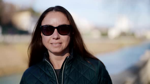 Portrait of Pretty Brunette Woman with Dark Sunglasses in Small City in Sunny Day