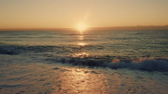 Ocean Waves Splash Into the Sand at Sunset Light