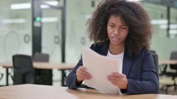 Displeased African Businesswoman with Loss Reading Documents
