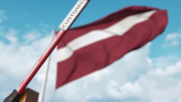 Barrier Gate with CUSTOMS Sign Closed at Flag of Latvia