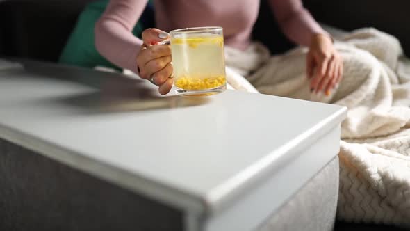 Slow Motion Woman's Hand Puts Pills Off the Table and Puts Sea Buckthorn Tea