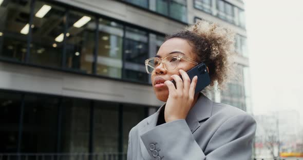 A Woman Using Mobile Phone While Standing Near an Office Building