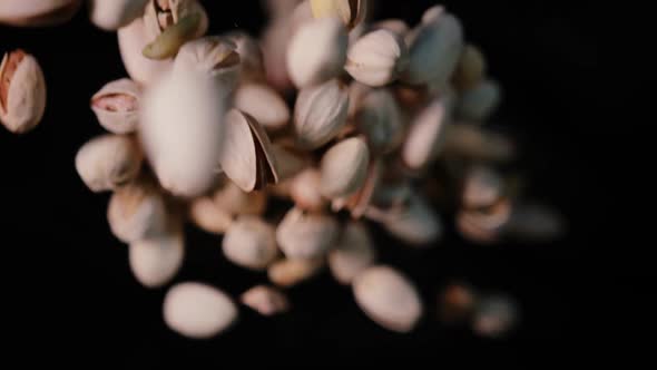 Closeup Shot of Salted Pistachios Flying Up Against Black Background in Slow Motion