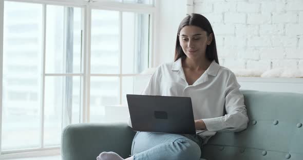 Thoughtful Young Woman Freelancer Types on Laptop