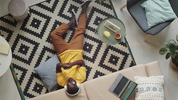 Black Man in Headphones Sitting on Floor and Using Smartphone