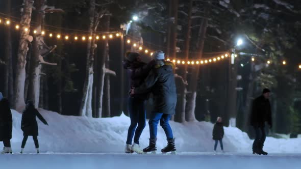 Happy Girl in Jacket Dances with Boyfriend on Skating Rink