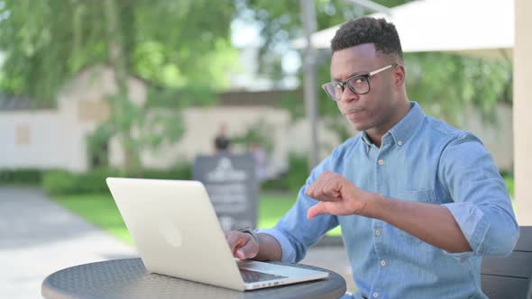 Thumbs Down By African Man with Laptop in Outdoor Cafe