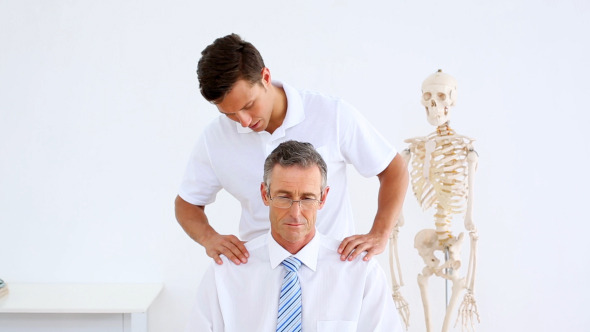Physiotherapist Giving Businessman A Shoulder Rub