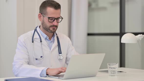 Male Doctor Working on Laptop in Hospital